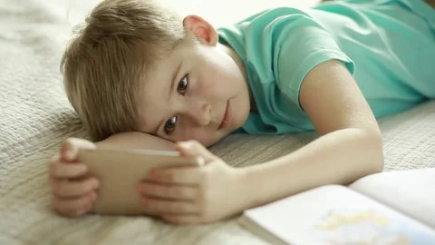  Boy looking at a smart phone while lying on the bed. Stock Footage 72869995