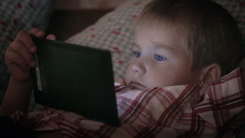 Boy looking at tablet computer at night Video stock 94716485