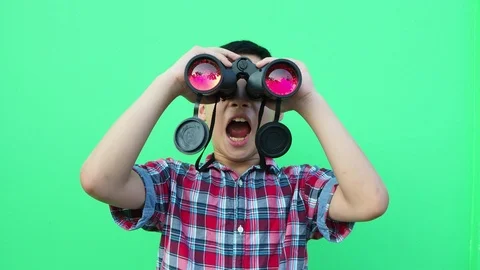 Boy looking through binoculars in front of green screen Stock Footage 89263200