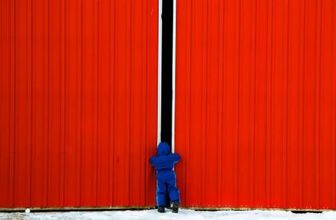 Boy looking through gap in doors (4-5 years) Stock Photos