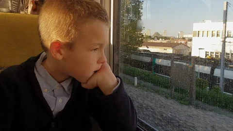 Boy looking through train window trying to distract from thoughts Stock Footage 124622620