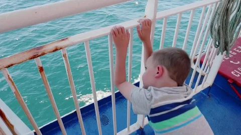 A boy looking off top of Ferry while traveling across the ocean water Stock Footage 77360924