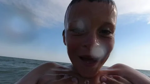 The boy looks at the camera and dives underwater with it. Sea and vacation. Video stock 263119462