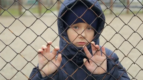The boy looks at the camera through the grid. The child's portrait Stockbeeldmateriaal 84085600