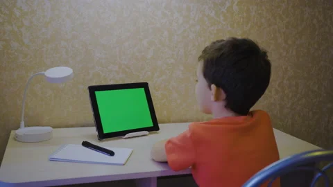 A boy looks into a chroma key tablet. Greenscreen Video stock 171416440