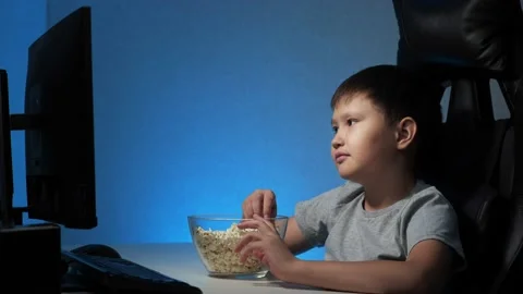 Boy looks at the computer funny video and eats popcorn Stock Footage 156890623