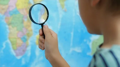 The boy looks at the map through a magnifying glass, slow motion Stock Footage 121136919