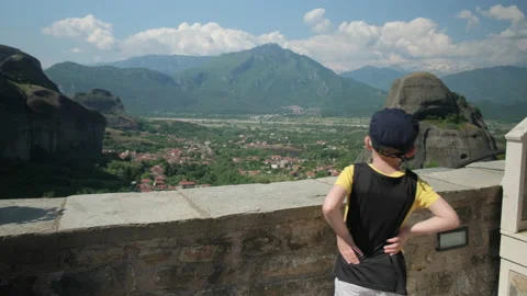 The boy looks at the mountains from the observation deck. Stockbeeldmateriaal 225849736