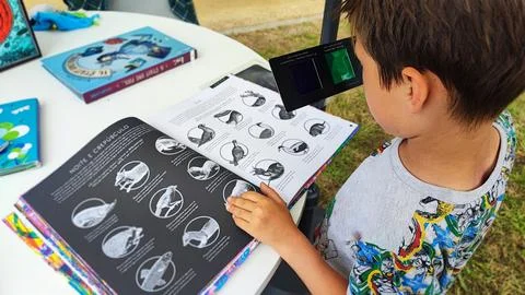 A boy looks at a multi-colored book through 3D glasses. Foto stock