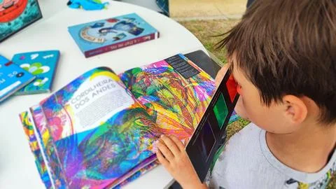 A boy looks at a multi-colored book through 3D glasses. Foto stock