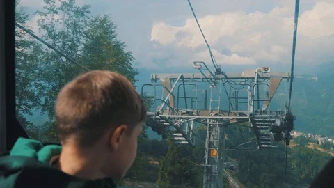 The boy looks out the window of the cableway. Beautiful landscape, mountains Stock-Footage 107854990