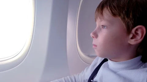 Boy looks out the window while flying in an airplane. Video stock 116590166