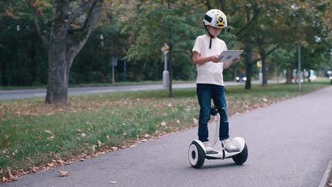 The boy looks at the screen of the tablet, rides on a GyroScooter Video stock 117421954