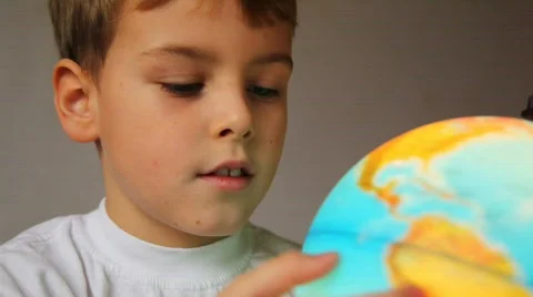 Boy looks at shone globe and rotates it Stock Footage