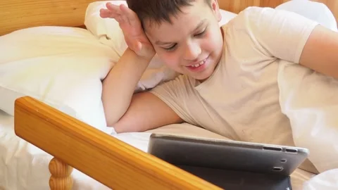 Boy looks at the tablet in the evening or at night before going to bed 動画素材 191564530