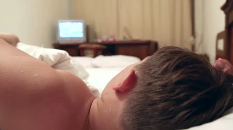 The boy is lying in bed and watching TV Stock Footage 52529732
