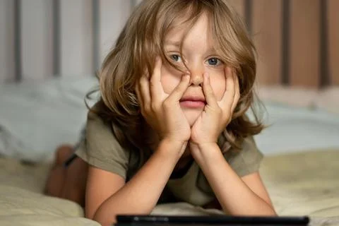 Boy lying on the bed using digital tablet computer playing games or watching Stock Photos