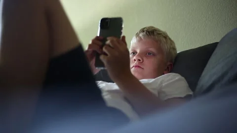 Boy lying on bed using smart phone Vídeos de archivo 135691741