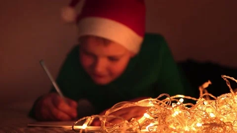 A boy lying on the bed writes a letter to Santa Claus, blurred frame. Stock Footage 165395629
