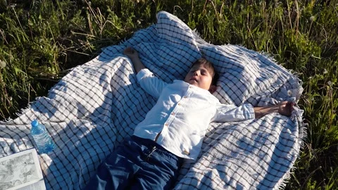 The boy is lying on the bedspread with his arms outstretched. The child is lying Stock Footage 156037662