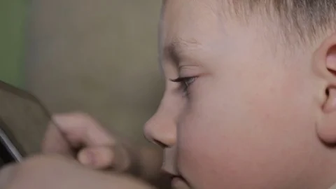 The boy is lying on the couch and is playing on the tablet Stock Footage 73570681