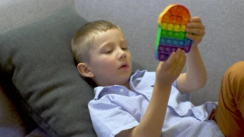 The boy is lying on the couch and playing pop-it Video stock 168074341