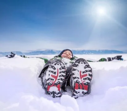 Boy lying in deep snow on the mountain hill Stock Photos