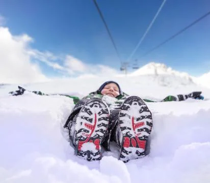 Boy lying in deep snow on the mountain hill Stock Photos