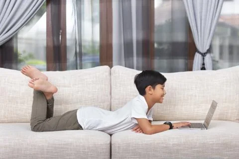 Boy lying down and using laptop Stock Photos