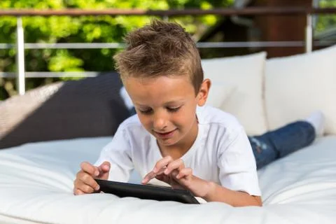 Boy lying down with his tablet Stock Photos
