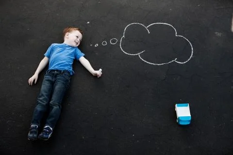 Boy lying on floor with chalk thought bubble Stock Photos