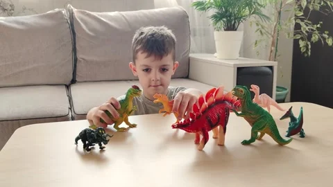 A boy lying on the floor plays with his favorite toys, bright figures of Stock Footage 272180536