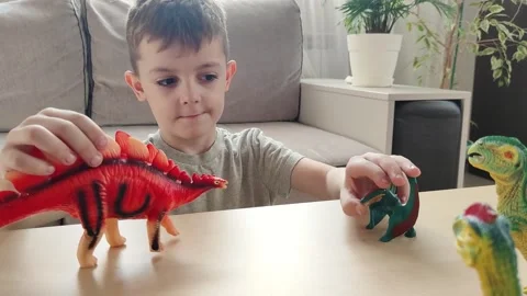 A boy lying on the floor plays with his favorite toys, bright figures of Stock Footage 272180563