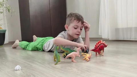 A boy lying on the floor plays with his favorite toys, bright figures of Stock Footage 272180592