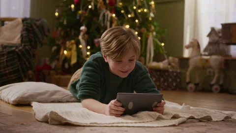 Boy Lying on Floor Using Digital Tablet near Christmas Tree Stock-Footage 346884701
