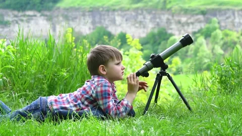 Boy lying in the grass with a spyglass Stock Footage 154505984