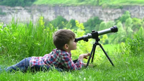 Boy lying in the grass with a spyglass Stock Footage 154505986
