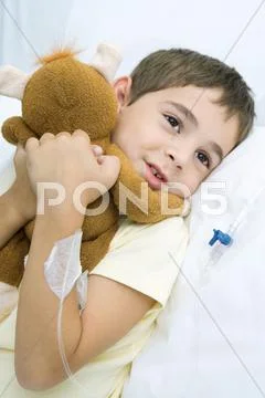 Boy Lying In Hospital Bed With Iv Drip In Arm, Hugging Stuffed Animal