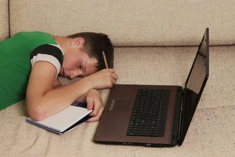 Boy lying with a laptop on the couch. Stock Photos