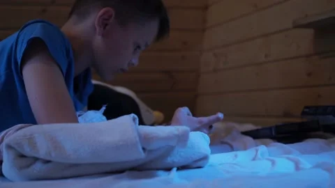 The boy is lying on the mattress and playing with the phone. esports on a tablet Stock Footage 167694111