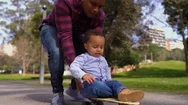 Boy Lying On Skateboard, Rolling With Fathers Help Stock Footage