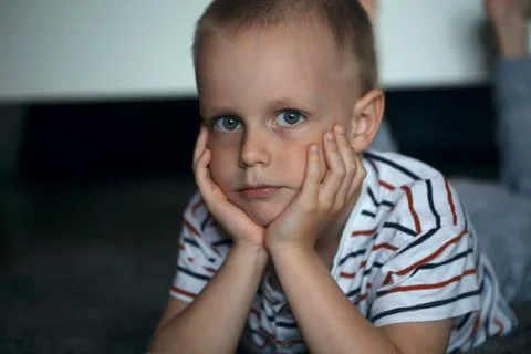 Boy lying on the sofa and propping his face with his hands Stock Photos