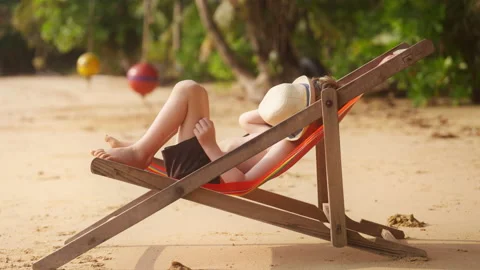 Boy Lying On Sun Lounger With Hat On His Face Stock Footage 239192692