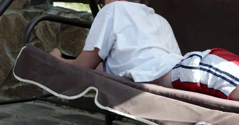 Boy Lying on the Swing Bench and Playing Game on Smartphone Video stock 64778769