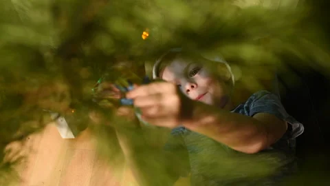 Boy lying under the Christmas tree and hang Christmas decorations Stock-Footage 116996427