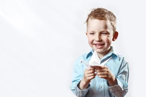 Boy made origami crane out of paper and rejoices on a light background Stock Photos
