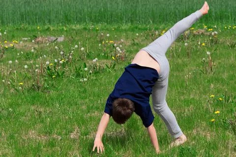 Boy makes an acrobatic wheel. On the grass. Foto stock