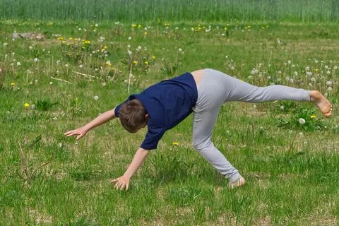 Boy makes an acrobatic wheel. On the grass. Stock Photos