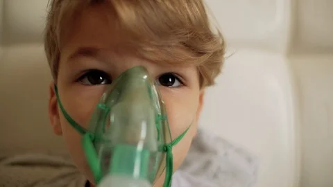 The boy makes inhalation while sitting on the bed.the child inhales steam Stock Footage 103697428