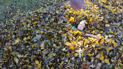 A boy makes a leaf angel (snow angel in the leaves) Stock Footage 93890445